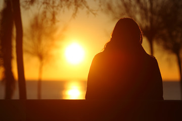 Silhouette of a lonely woman watching sunset in winter