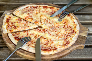 Fresh italian pizza Margherita pizza on wooden chopping board, rustic background