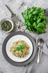 Cooked spaghetti pasta on a plate with basil pesto and Parmesan cheese, Italy food, healthy concept, vegetarian