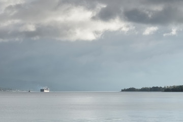 Ship on sea horizon under huge dark storm sky and clouds