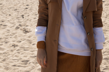 Girl in the beige coat on the beach.