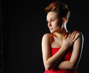 Sensual young lady in red dress posing an studio. Beauty, fashion concept.