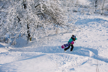 Leisure, sport concept - amateur snowboarder go up with her board on snowy slope