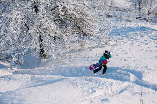 Leisure, sport concept - amateur snowboarder go up with her board on snowy slope