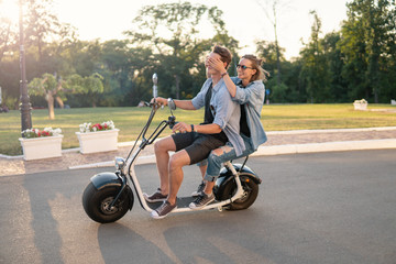 Lovely young couple driving electric bike. Modern city transportation