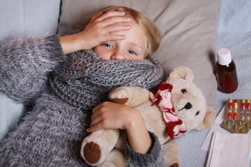 Sick little girl lying in the bed with her toy