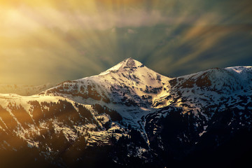 Fototapeta na wymiar Glowing light behind winter mountain peak