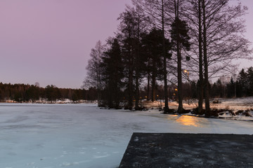 Sunset on the frozen lake in the woods. Colorful winter sunset. Quiet Winter Evening in Nature. Fantastic evening winter landscape. Norway