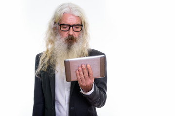 Studio shot of senior bearded businessman using digital tablet
