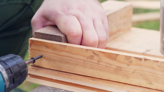 Man screwing screw in wooden plank