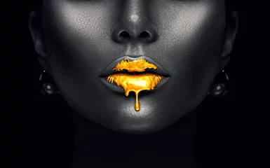 Papier Peint photo Lèvres fantaisie De la peinture dorée coule des lèvres sexy, des gouttes de liquide doré sur la bouche de la belle fille modèle, un maquillage abstrait créatif. Visage de femme de beauté isolé sur fond noir