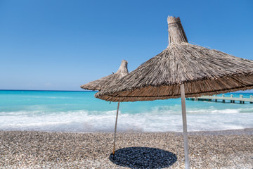 tropical umbrellas on a island beach. Blue ocean on background. Tourism travel concept
