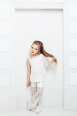 Cute little blond girl wearing white casual clothes on a white background. Fashion style.