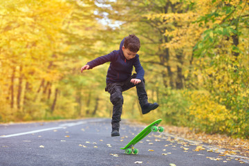 Fototapeta premium Kid skateboarder doing skateboard tricks in autumn environment