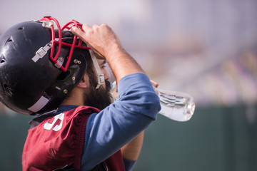 american football player drinking water after hard training
