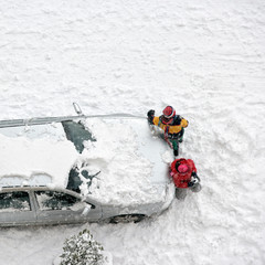 Children play in snow around cars in parking lot