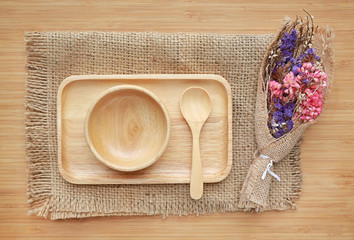 Wooden tray, bowl and spoon on sack against wood board background