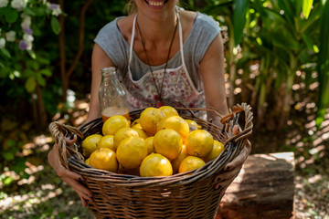A woman carrying a wicker basket full of fresh lemons. 