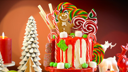 On trend candyland Christmas drip cake with Christmas lights bokeh background.