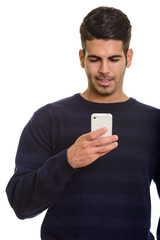 Young happy Persian man smiling and using mobile phone