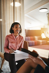 Smiling young businesswoman sitting with an office colleague dis