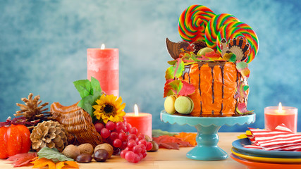 On trend Thanksgiving candyland novelty drip cake with colorful Fall leaves and cornucopia table...