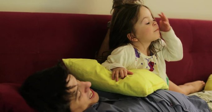 Little girl and father together at sofa watching TV, child nose picking