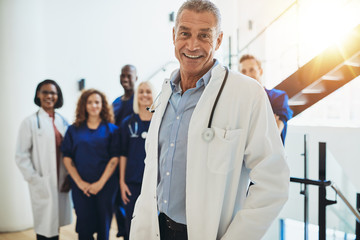 Smiling mature doctor standing in a hospital with his staff
