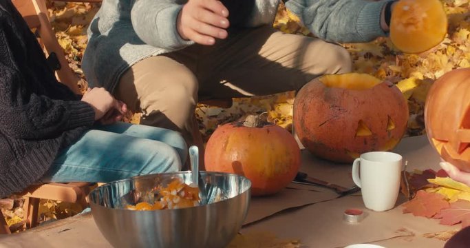 Father and daughter, carving pumpkins for Halloween on the table outdoors in the backyard. 4K UHD 60 FPS
