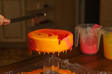 Mousse yogurt cake. The girl creates a drawing of mousse on the cake. Frozen mirror icing on the cake. Culinary masterpieces.