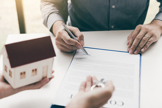 Hand client signing contract paper a real estate or mortgage contract.