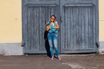 Portrait of a smiling woman standing with her skateboard next to the old wooden wall.