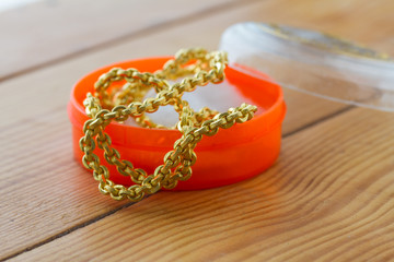gold necklace in orange cup on table.