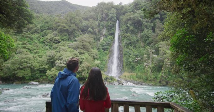 New Zealand tourists at waterfall nature landscape. People looking at Waterfall Thunder Creek Falls and Haast River, Mt. Aspiring National Park. RED EPIC SLOW MOTION.