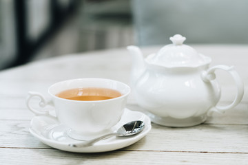 Cup of english tea with white pot and cup on luxury wooden table, copy space 