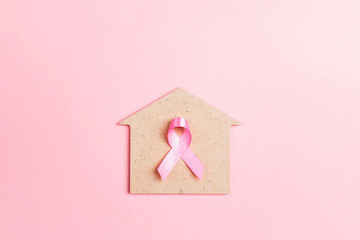 Pink ribbon with house symbol on pink background for Breast Cancer Awareness symbol.