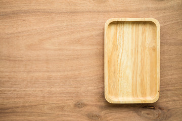 Top view of unused brand new brown handmade wooden dish plate on wooden table background