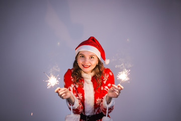 Christmas, holidays and people concept - woman in santa suit with lights and sparkles laughing.