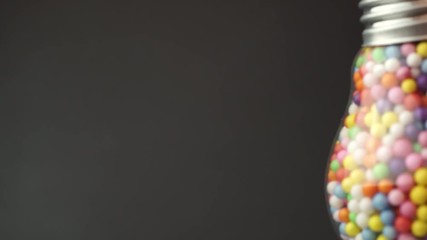 Lightbulb filled with colored ball dark background, macro view. Best idea concept.