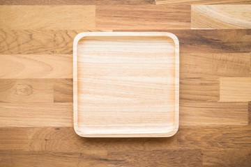 Top view of unused brand new brown handmade wooden dish plate on wooden table background
