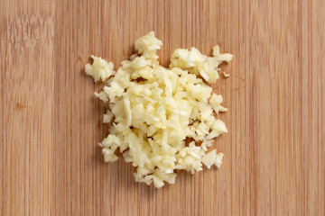 Garlic minced on wooden plate in the middle. Top view