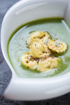 Closeup of cream-soup with broccoli topped with tortellini, selective focus, vertical shot