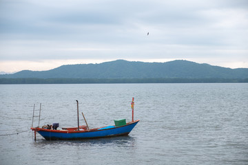 Fototapeta premium wooden boat For saltwater fishing in the sea during the morning sunrise.Use for website/banner background, backdrop, montage menu.