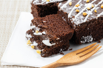 chocolate brownies on a white paper. And there is a spoon on the side.