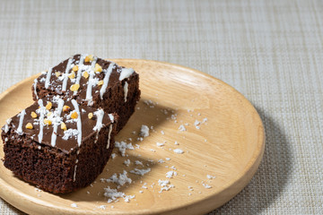 Two chocolate brownies On a plate of wood.