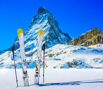 Ski in winter season, mountains and ski touring backcountry equipments on the top of snowy mountains in sunny day with Matterhorn in background, Zermatt in Swiss Alps.