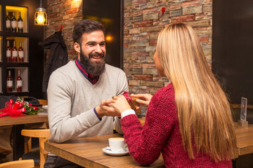 Man giving a present to his girlfriend in cafe and she is surprise