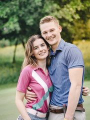 Happy golfer couple hugging together at green field outdoor.