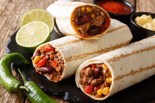 Fast food grilled burrito with beef and vegetables close-up on the table. horizontal, rustic