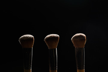 Professional makeup brush with powder on a black background